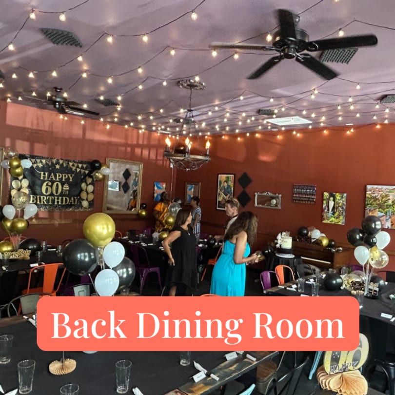 A decorated dining room with string lights, balloons, and a "Happy 60th Birthday" banner.