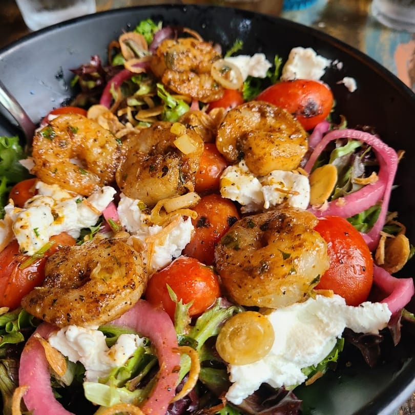 Succotash Southern and Creole Kitchen's shrimp salad with greens, tomatoes, pickled onions, and cheese.