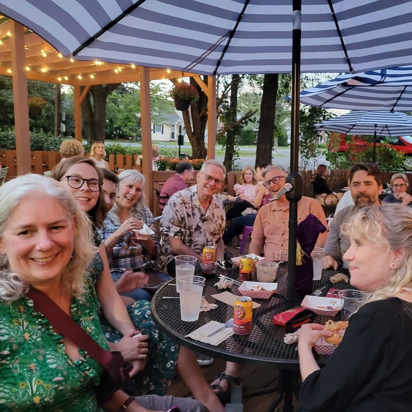 Smiling patrons enjoy food and drinks on the outdoor patio of Succotash Southern and Creole Kitchen.