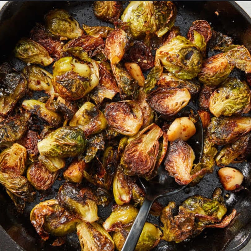 Close-up of roasted Brussels sprouts with garlic in a cast iron pan, ready to be served.